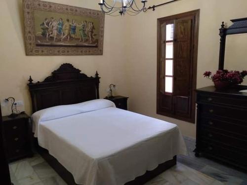 1 dormitorio con 1 cama y una pintura en la pared en Casa Villa Las Palmeras, en Arriate
