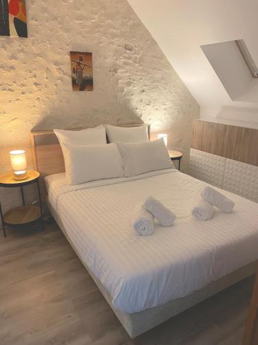 une chambre avec un lit blanc avec deux serviettes dessus dans l'établissement La Maison des anges avec jardin : proche beauval, à Billy