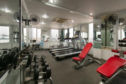 a gym with several tread machines and red chairs at San Hanoi Hotel in Hanoi