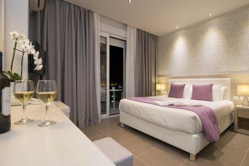 a bedroom with a bed and two glasses of wine at Angelica Hotel in Limenas
