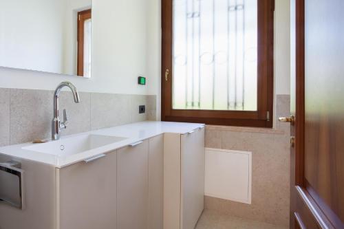 eine weiße Küche mit einem Waschbecken und einem Fenster in der Unterkunft Villa Carducci in Torri del Benaco