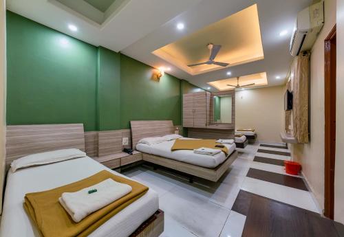 Zimmer mit 3 Betten und einer grünen Wand in der Unterkunft Hotel RadhaKrishna-Couple Friendly in Kolhapur