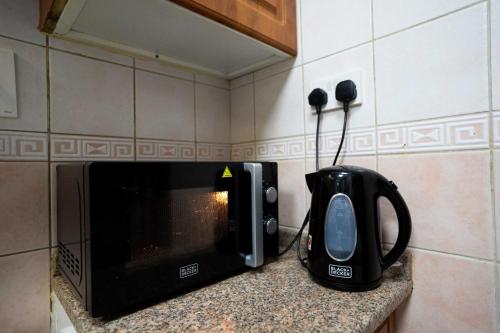 Un four micro-ondes est installé sur un comptoir à côté d'un grille-pain. dans l'établissement Robin Hostel Dubai, à Dubaï