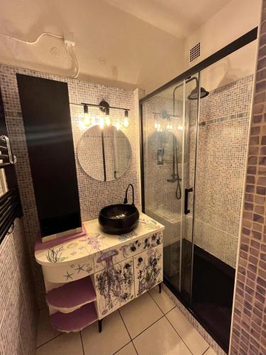 une salle de bain avec un lavabo et une douche avec un miroir dans l'établissement Petit appartement à 50m à pied de la mer, à Fréjus