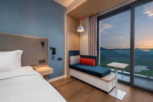 ein Hotelzimmer mit einem Bett, einem Stuhl und einem Fenster in der Unterkunft Holiday Inn Express Wawu Mountain, an IHG Hotel in Meishan