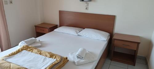 a bedroom with a bed with white sheets and towels at Kiparissis Apartments in Kriopigi