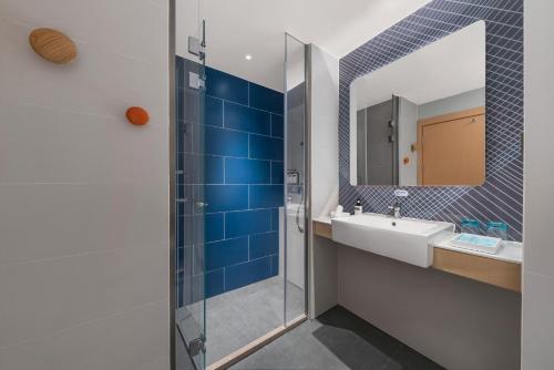 ein Bad mit einem Waschbecken und einem Spiegel in der Unterkunft Holiday Inn Express Wawu Mountain, an IHG Hotel in Meishan