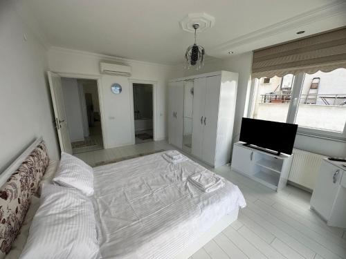 a white bedroom with a bed and a television at TRABZON PANORAMA APART in Trabzon