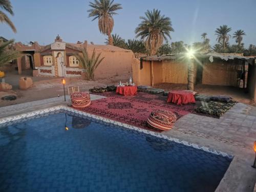 a swimming pool with a table and chairs next to a house at Camp Desert Stars in Mhamid
