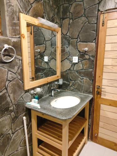 a bathroom with a sink and a stone wall at Dream Nest Resorts in Skardu