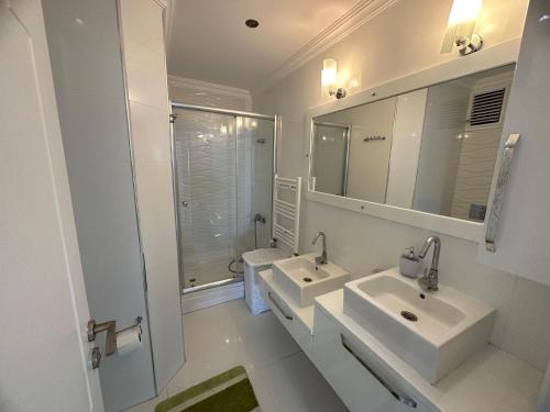 a white bathroom with two sinks and a shower at TRABZON PANORAMA APART in Trabzon
