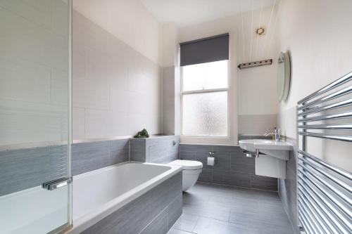 a bathroom with a tub and a toilet and a sink at 1 bed Clapham Junction apartment in London