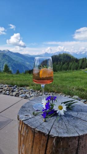 a glass of wine sitting on a wooden table with flowers at Almgasthaus Glocknerblick in Großkirchheim