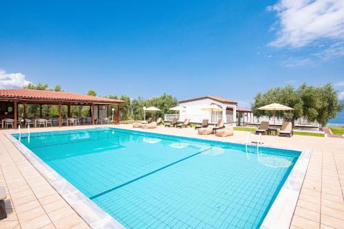 a large swimming pool with chairs and umbrellas at Blue Marine Village in Chalkida