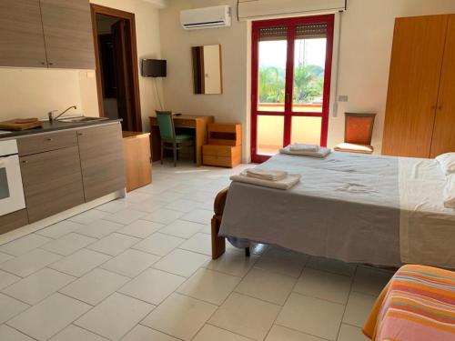 a bedroom with a large bed and a kitchen at Villaggio Magna Grecia in Lazzaro