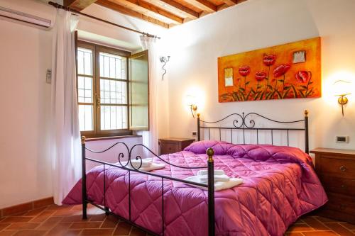 een slaapkamer met een roze bed en een schilderij aan de muur bij Casa Vacanza Il Carpignone 7 in Massa Marittima