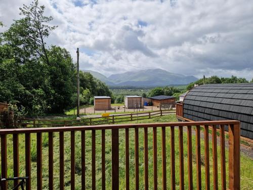 a fence with a view of mountains in the distance at Squirrel Lodge in Roybridge