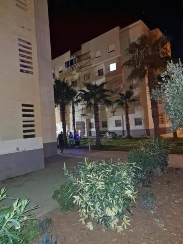 een gebouw met palmbomen en planten ervoor bij appartement les Jardins de la Moulouya in Saidia 