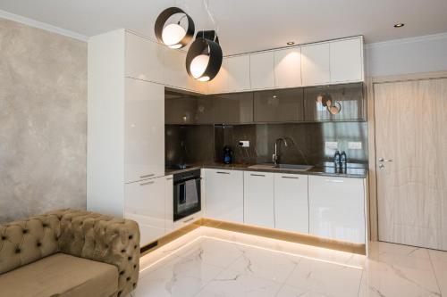 a kitchen with white cabinets and a couch at Luxury Martina apartment in Veliko Tŭrnovo
