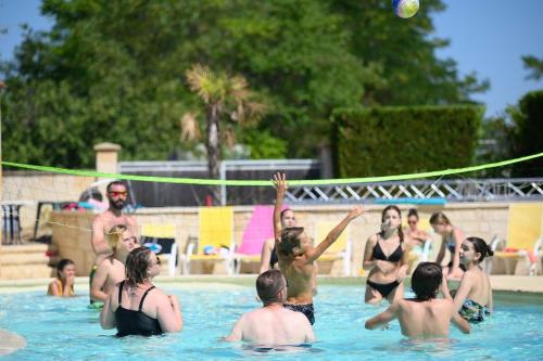 a group of people playing volleyball in a swimming pool at Le Clos de Barbey in Bauduen