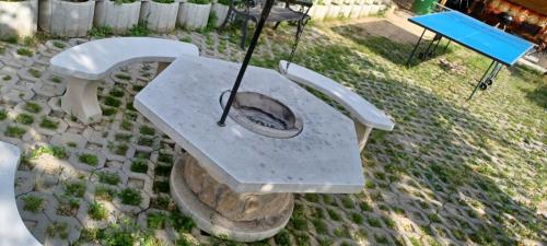 a concrete bench with an umbrella and two chairs at Bé-La 2 Vendégház in Szomolya