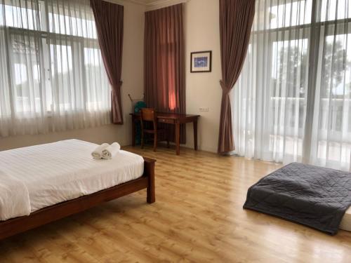 a bedroom with a bed and a desk and windows at Sealinks city - Tvila in Phan Thiet
