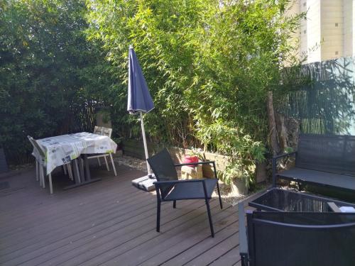 un patio con sombrilla, mesa y sillas en ANGLET petite Maison à 2 kms des plages et de Biarritz, en Anglet