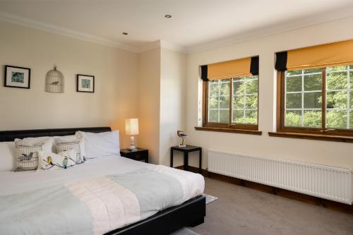 a bedroom with a large bed and two windows at Achnagairn Estate - Self-catering Mini Manors in Beauly