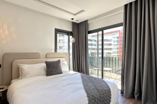 a bedroom with a large bed and a balcony at Sunny 2 Bedrooms - By AppartAli in Casablanca