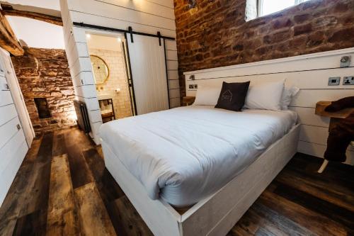 Bashall Barn في كليثروي: سرير في غرفة بجدار من الطوب