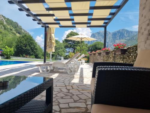 a patio with chairs and an umbrella next to a pool at Milas Trojica Kotor in Kotor