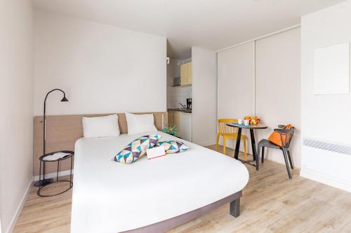 a bedroom with a white bed and a table at Appart'City Classic Rennes Ouest in Rennes