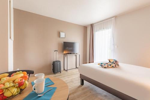 um quarto com uma cama e uma tigela de fruta numa mesa em Appart'City Classic Rennes Ouest em Rennes