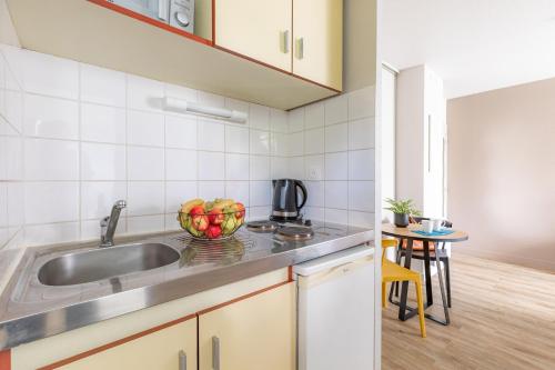 a kitchen with a sink and a bowl of fruit on the counter at Appart'City Classic Rennes Ouest in Rennes