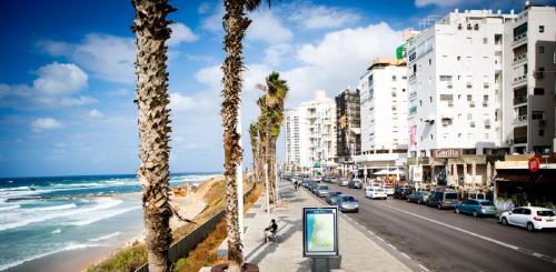 a city street with palm trees and the ocean at חופים מול הים in Bat Yam