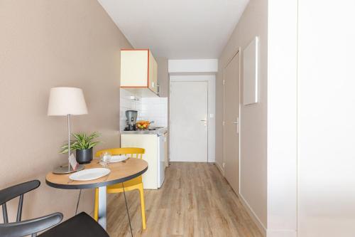 a small kitchen and dining room with a table and chairs at Appart'City Classic Rennes Ouest in Rennes
