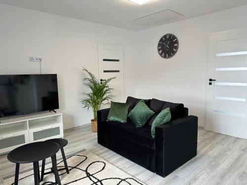 a living room with a black couch and a tv at Apartamenty Przy Deptaku in Świnoujście