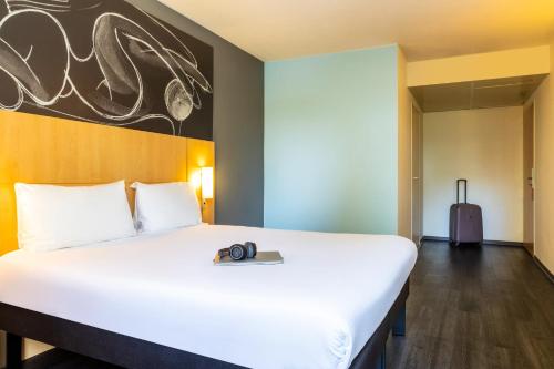 a large white bed in a room with a suitcase at ibis Paris Meudon Velizy in Meudon