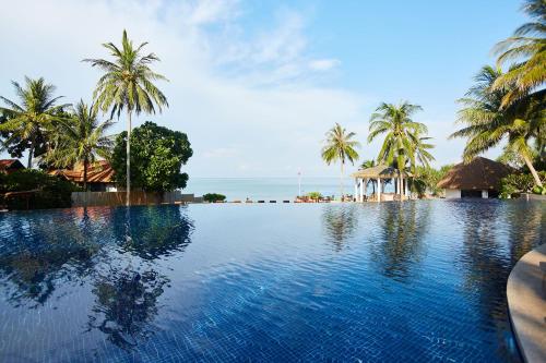 einen Pool mit Palmen und dem Meer in der Unterkunft Rawi Warin Resort And Spa - SHA Extra Plus in Ko Lanta