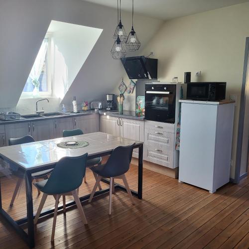 une cuisine avec une table et des chaises et un réfrigérateur blanc dans l'établissement La myssaline, à Cayeux-sur-Mer
