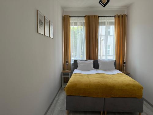 a bedroom with a bed with a yellow blanket at Apartamenty Przy Deptaku in Świnoujście
