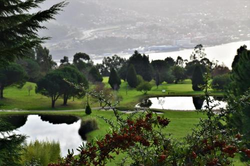 a golf course with a bridge and a pond at Hotel Bienestar Moaña in Moaña