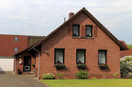 a red brick house with two windows and flower boxes at Ferienhaus am Ostfrieslandwanderweg, 15177 in Leer
