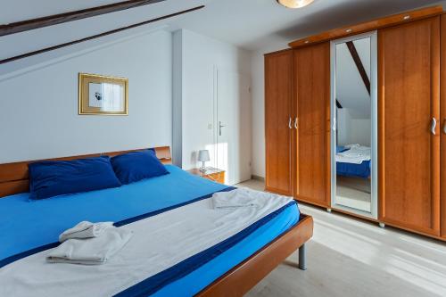 una camera con letto blu e armadi in legno di Apartment Skorin a Rogoznica (Rogosnizza)