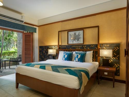 a bedroom with a large bed with blue pillows at Angsana Oasis Spa & Resort in Yelahanka