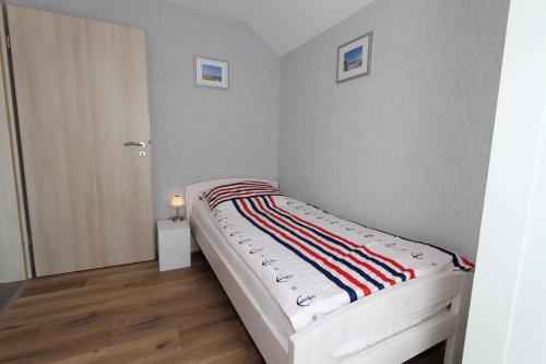 a small bedroom with a bed with a striped blanket at Ferienhaus am Ostfrieslandwanderweg, 15177 in Leer