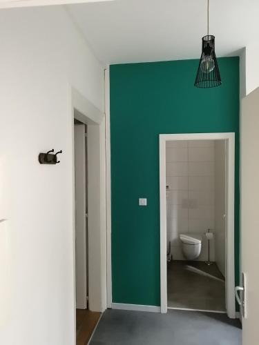 La salle de bains est pourvue d'un mur vert et de toilettes. dans l'établissement LE 1 