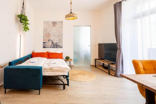 ein Wohnzimmer mit einem blauen Sofa und einem TV in der Unterkunft FeelgooD Apartments DELUXE Zwickau CityCenter mit TG-Stellplatz, Netflix und Waipu-TV in Zwickau