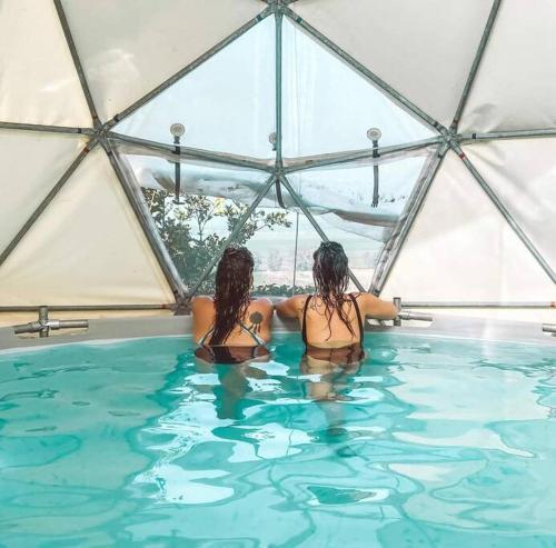two women in a swimming pool in a yurt at פשוט מים. יחידה קסומה עם נוף מרהיב ובריכה מחוממת in Gonen