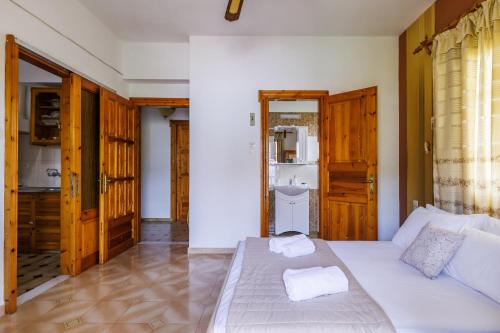 a bedroom with a white bed and a bathroom at Panagou Studios in Skopelos Town